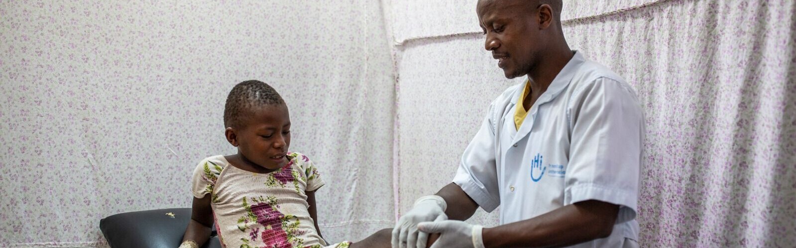 Ein Physiotherapeut von Handicap International untersucht Kizubizo aus dem DR Kongo, die beide Beine wegen eines Rebellenangriffs verloren hat
