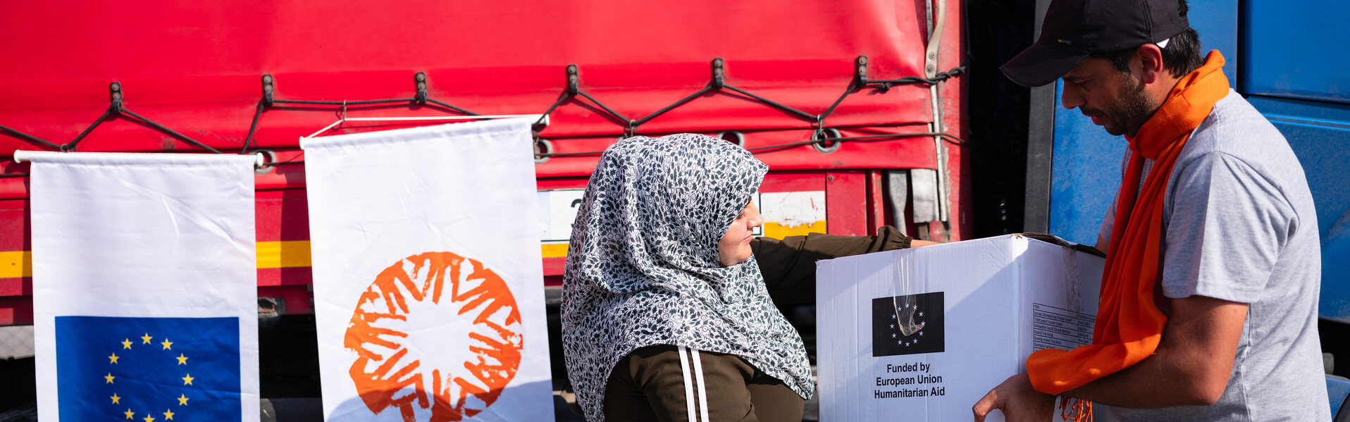 Eine Frau nimmt ein Hilfspaket von einem Helfer entgegen
