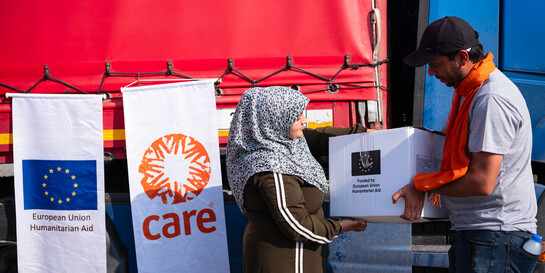 Eine Frau nimmt ein Hilfspaket von einem Helfer entgegen