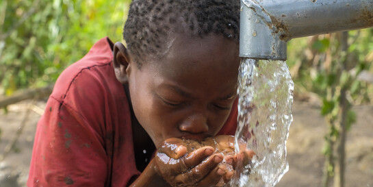 Ein Kind in Uganda am Wasserbrunnen