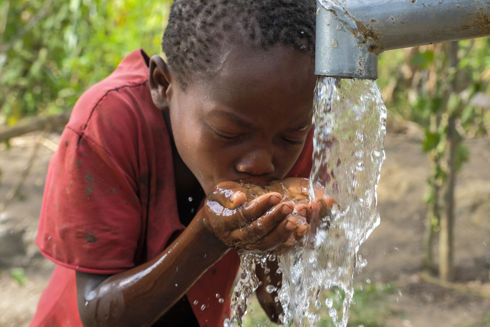 Ein Kind in Uganda am Wasserbrunnen