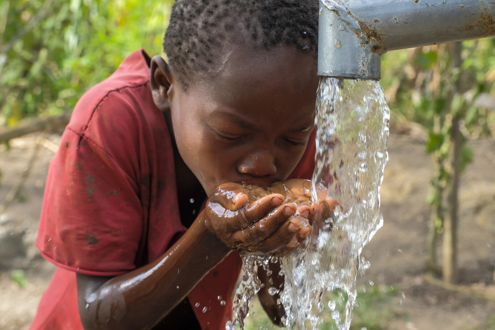 Ein Kind in Uganda am Wasserbrunnen