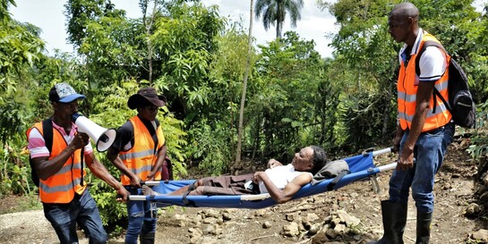 Katastrophenübung auf Haiti: Männer in Warnwesten transportieren eine Frau auf einer Krankenbahre