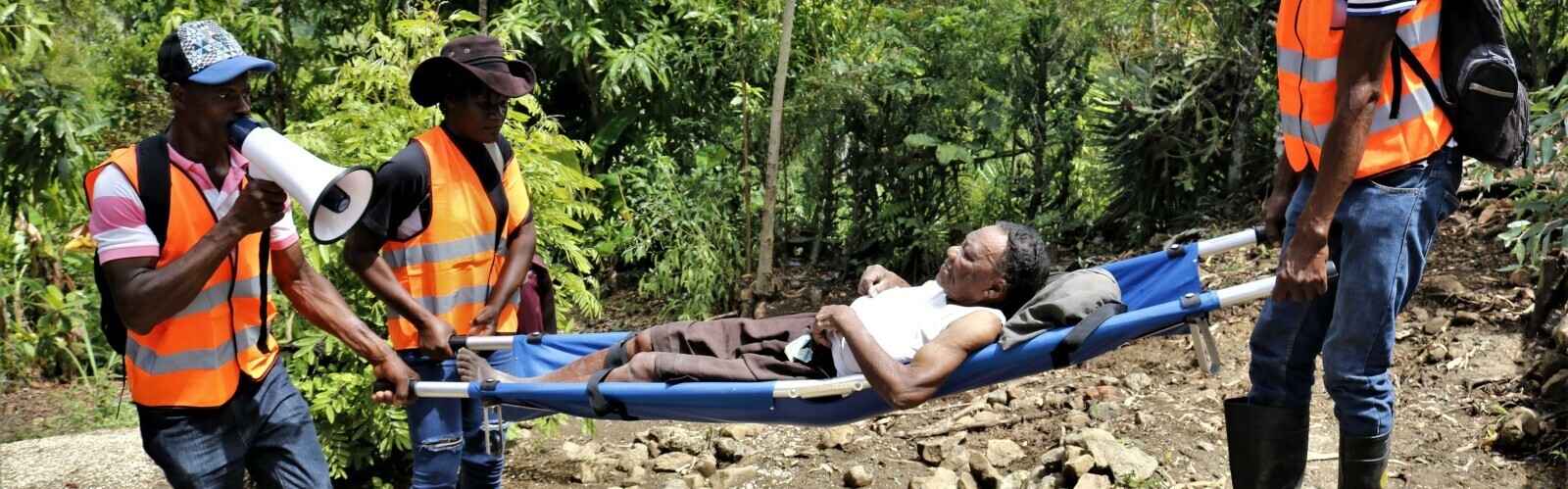 Katastrophenübung auf Haiti: Männer in Warnwesten transportieren eine Frau auf einer Krankenbahre