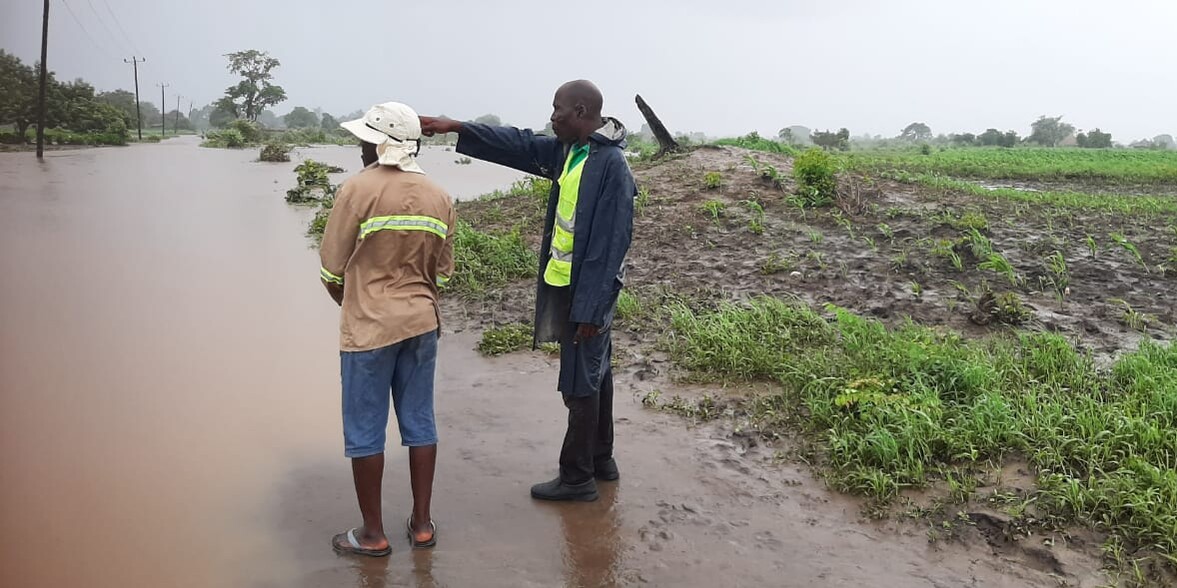 Zwei Männer stehen auf einer überfluteten Straße in Mosambik Zwei Männer stehen auf einer überfluteten Straße in Mosambik