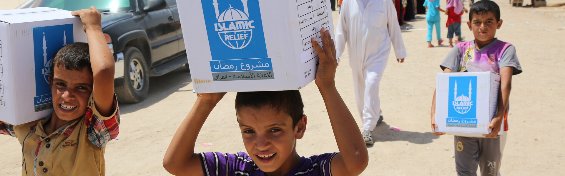 Kinder tragen Pakete mit Islamic Relief Logo.