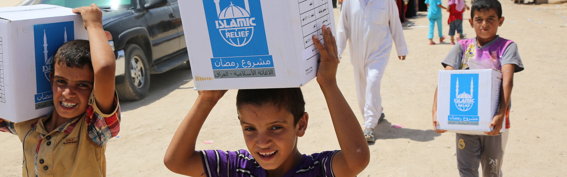 Kinder tragen Pakete mit Islamic Relief Logo.