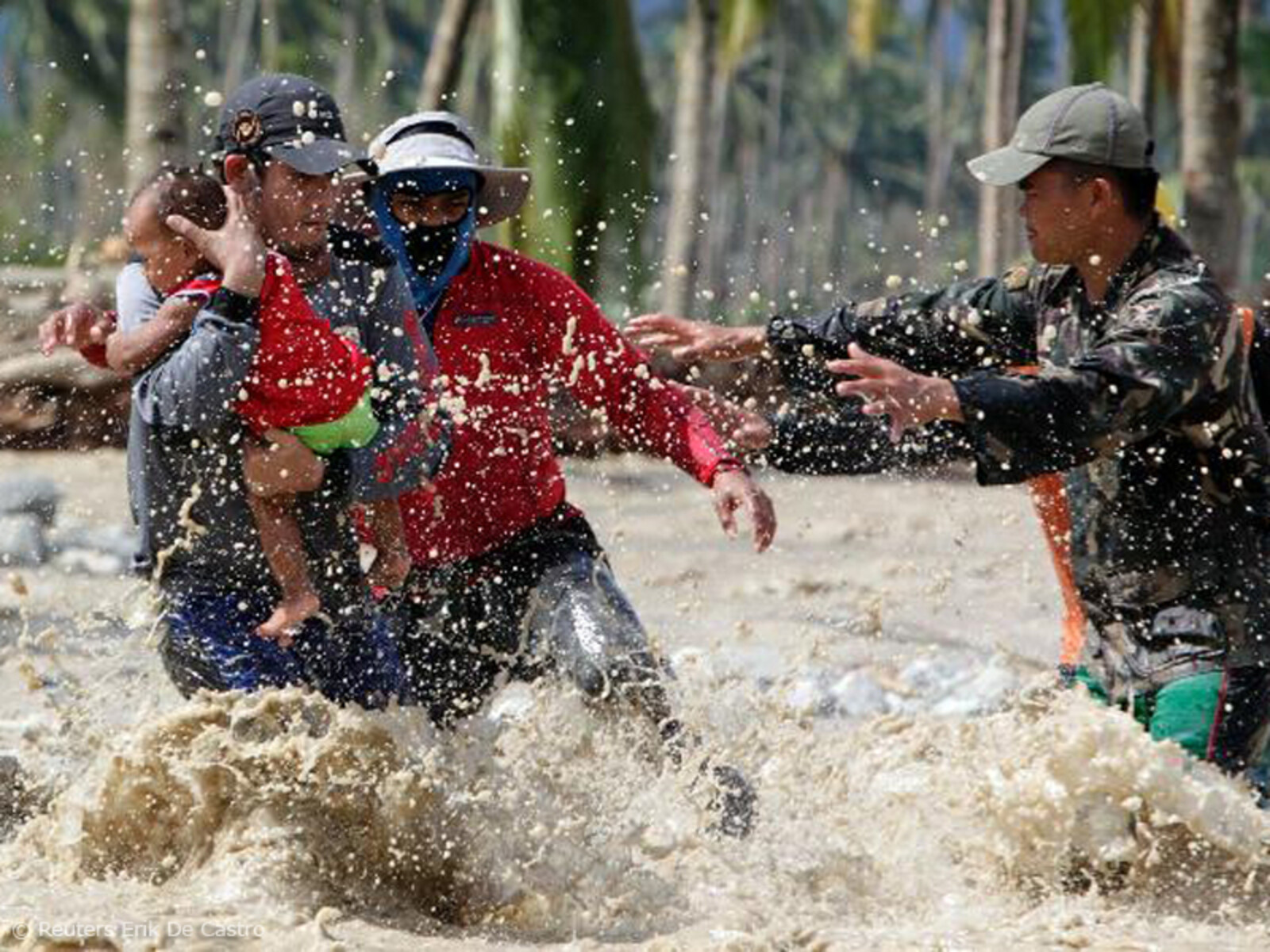 Männer mit Baby in den Fluten nach Taifun "Bopha" auf den Philippinen