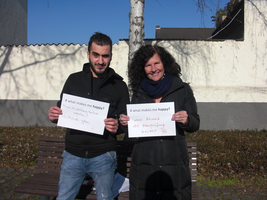 Frau und Mann halten in Deutschland jeweils Zettel hoch mit der Aufschrift "whatmakesmehappy"