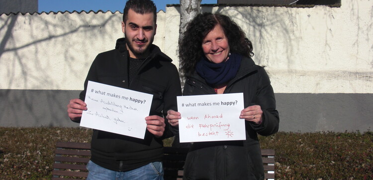 Frau und Mann halten in Deutschland jeweils Zettel hoch mit der Aufschrift "whatmakesmehappy"