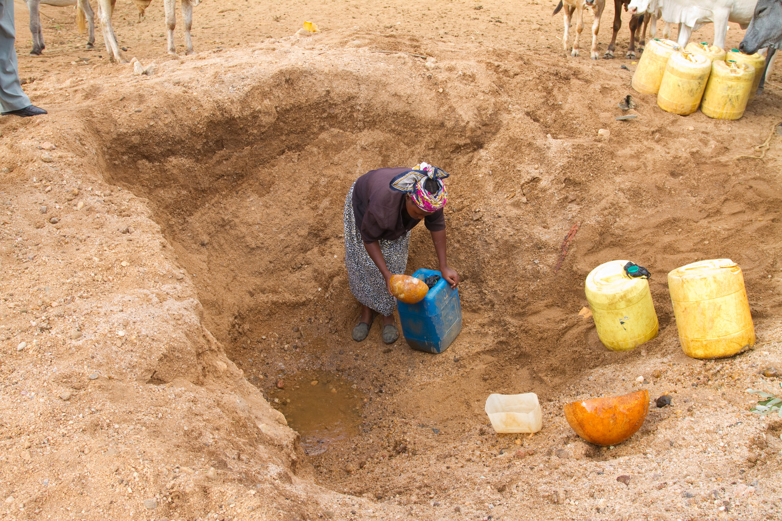 Eine Frau schöpft Wasser aus einem fast versiegten Brunnen. Während Dürreperioden in Afrika sterben jedes Jahr viele Menschen an Hunger und Wassermangel.