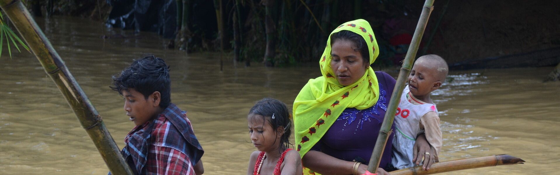 Eine Familie überquert einen überfluteten Weg im Flüchtlingsamp in Bangladesh.