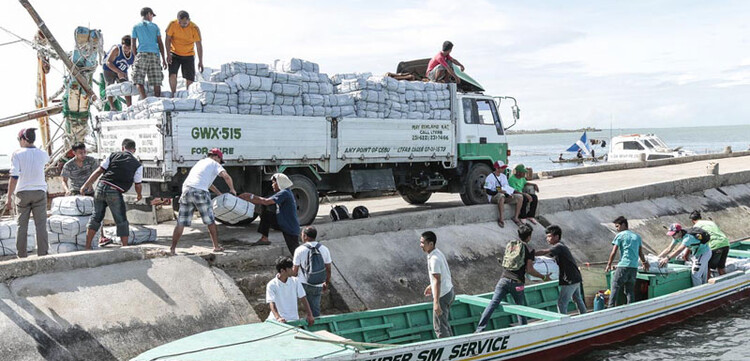 Hier werden Hilfspakete auf ein Boot umgepackt