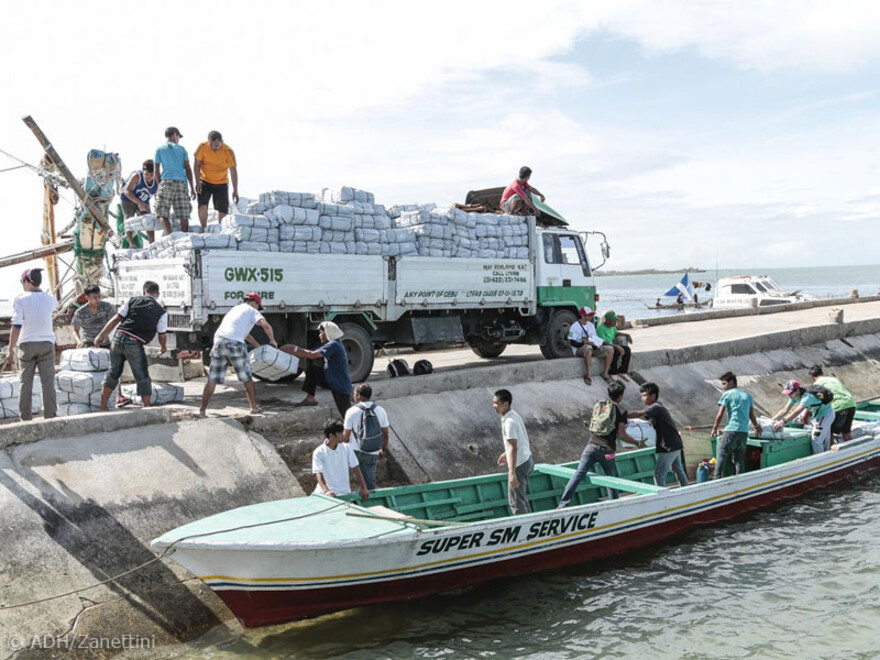 Hier werden Hilfspakete auf ein Boot umgepackt