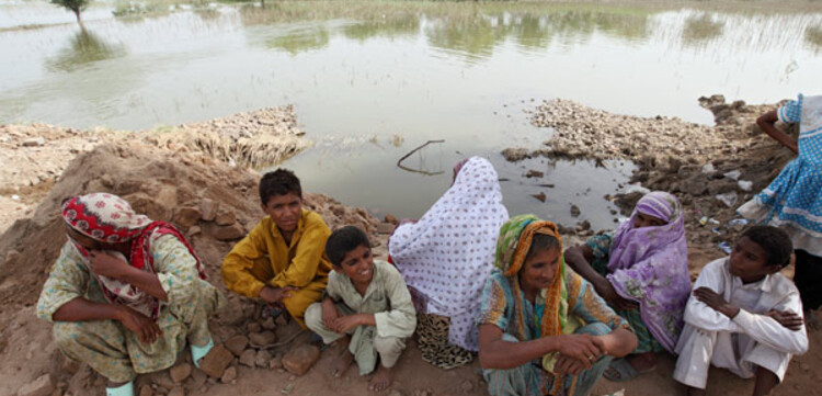 28.08.2010, Pakistan, Punjab Muzaffargarh- Hochwasser Pakistan. Frauen und Kinder sitzen am Rande überfluteter Felder.