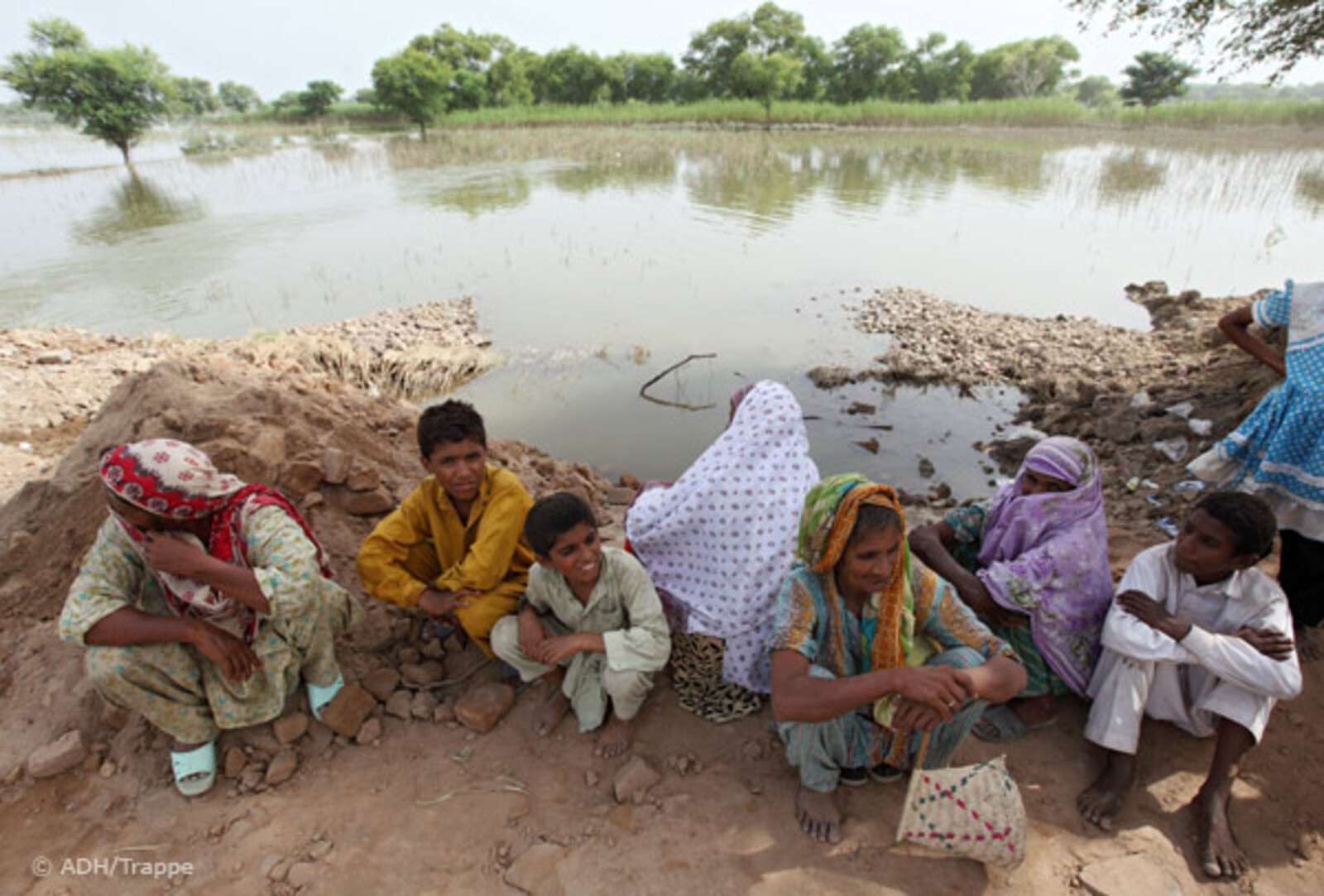 28.08.2010, Pakistan, Punjab Muzaffargarh- Hochwasser Pakistan. Frauen und Kinder sitzen am Rande überfluteter Felder.