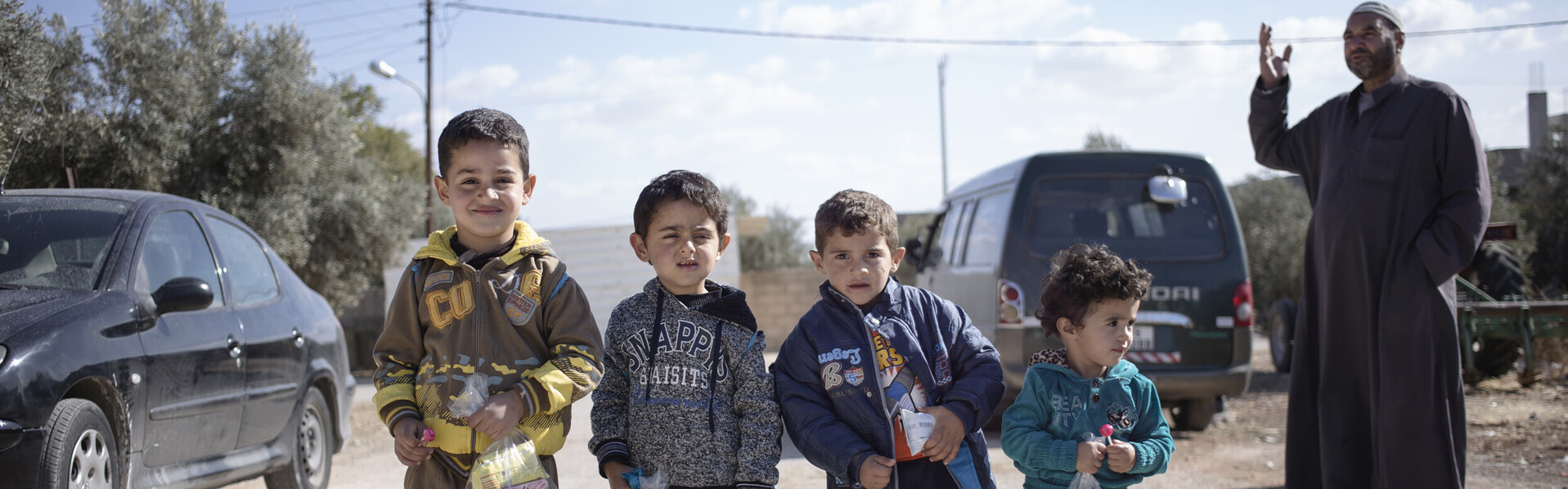 Kinder stehen auf der Straße. Ein Mann erzählt eine Geschichte. Die Kinder sind Flüchtlinge in Jordanien © Johanniter