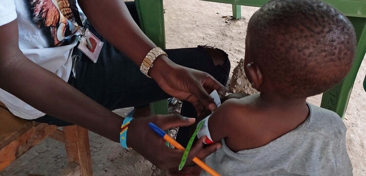 Ein Mann untersucht ein Kleinkind in Kakuma, Kenia Ein Mann untersucht ein Kleinkind in Kakuma, Kenia