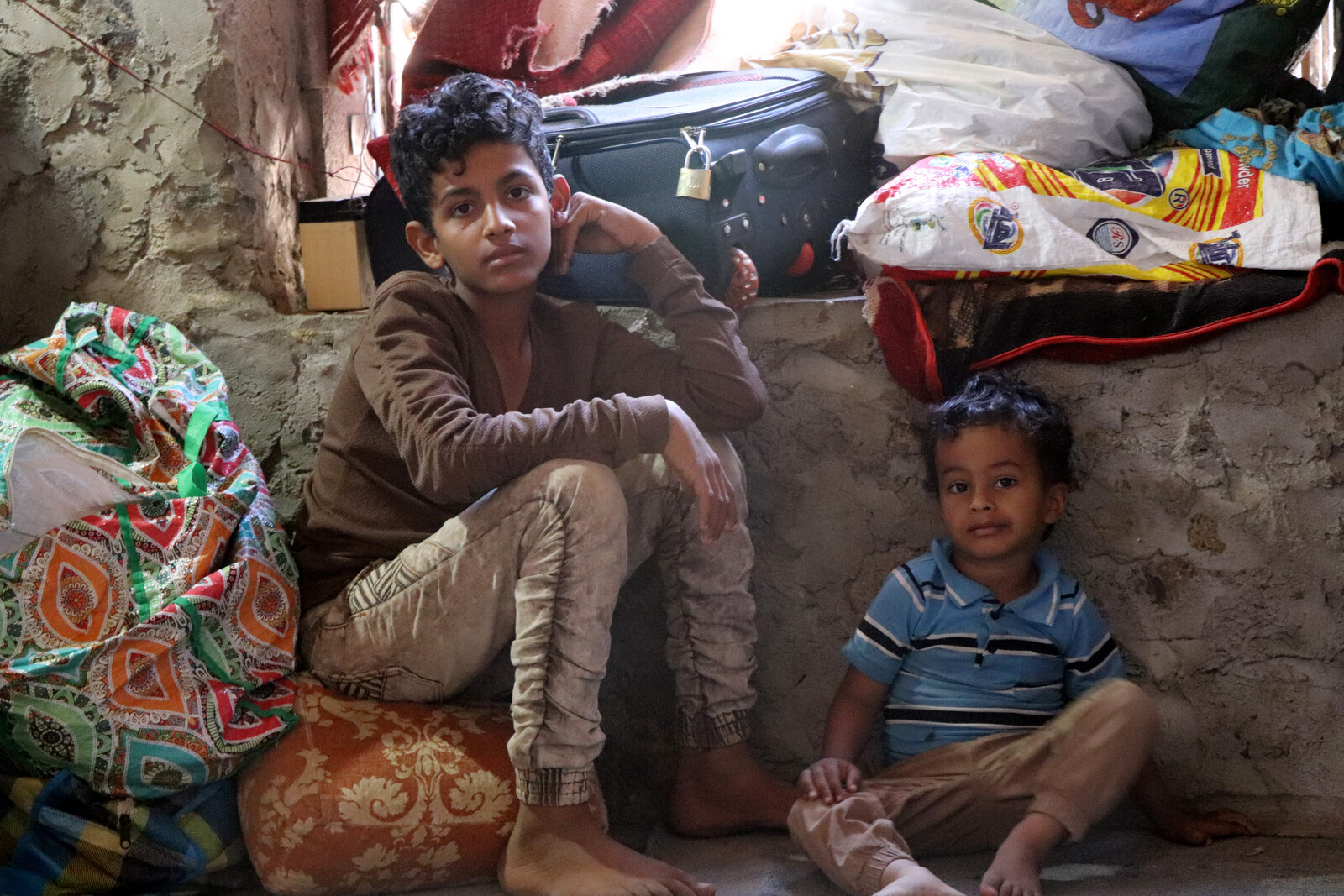 Zwei Kinder im Jemen passen auf die Habseligkeiten ihrer geflüchteten Familie auf 