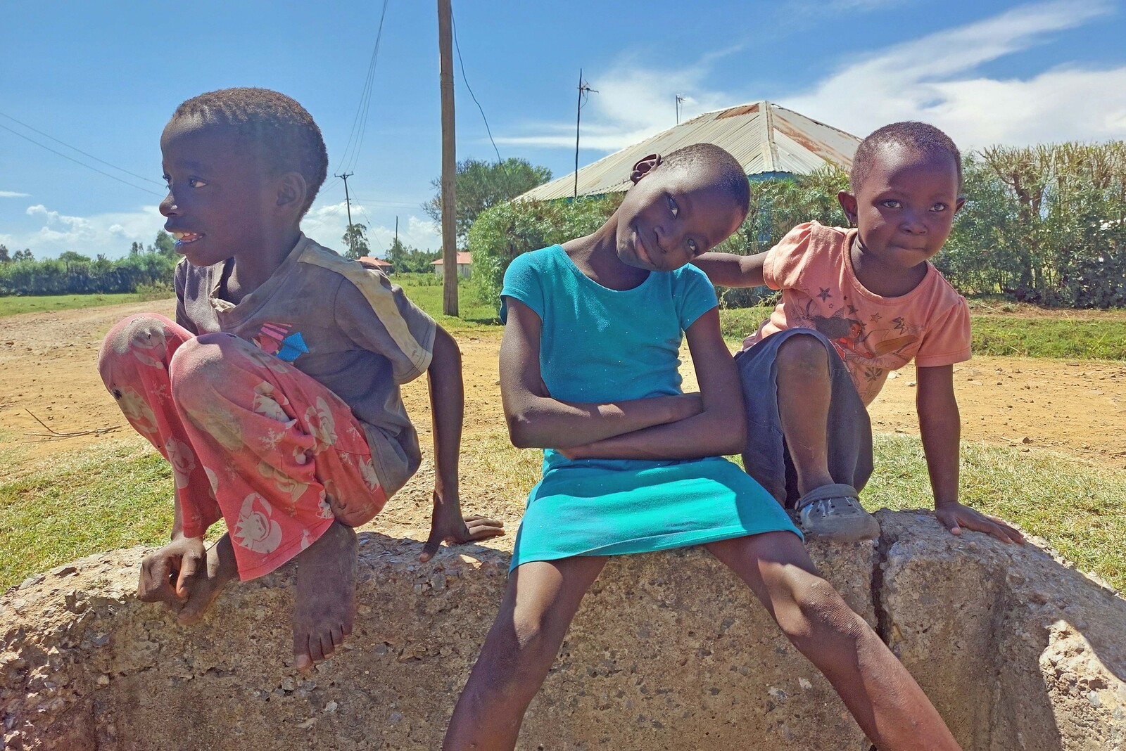 Drei Kinder sitzen in West-Kenia auf einer Mauer