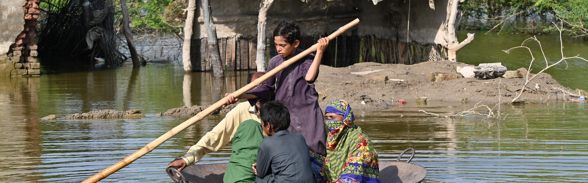 In einer großen Metallpfanne rettet sich eine Familie vor den Überschwemmungen in Pakistan