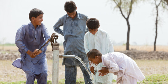Nach dem schweren Erdbeben in Pakistan waren viele Brunnen zerstört. Einige Jungen spielen an einer Wasserpumpe.
