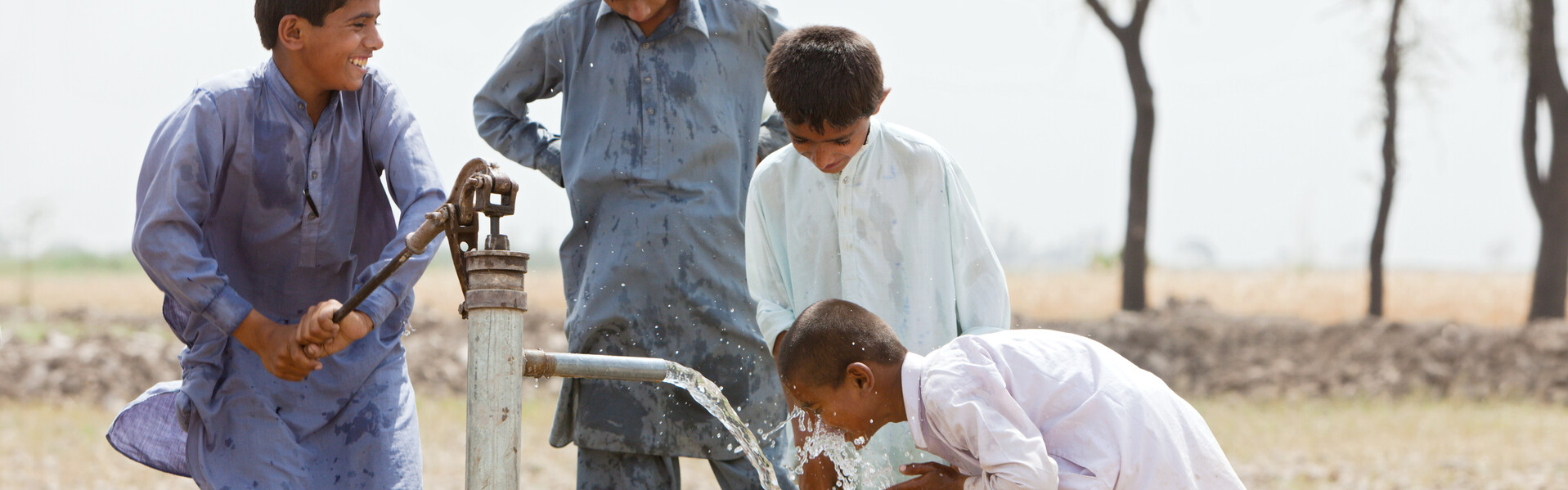 Nach dem schweren Erdbeben in Pakistan waren viele Brunnen zerstört. Einige Jungen spielen an einer Wasserpumpe.
