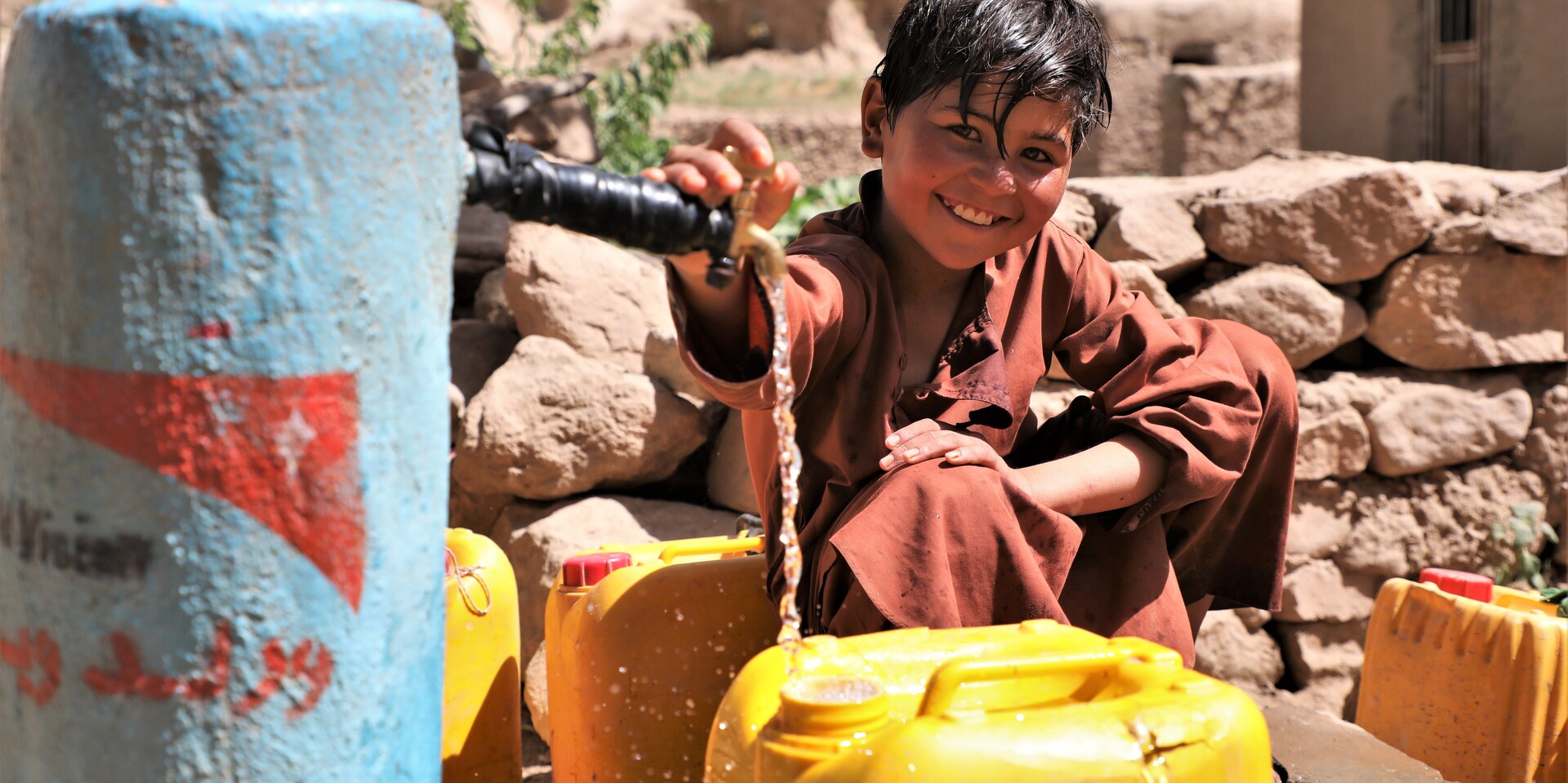 Ein Junge in Afghanistan füllt einen Kanister an einer Wasserstelle von World Vision
