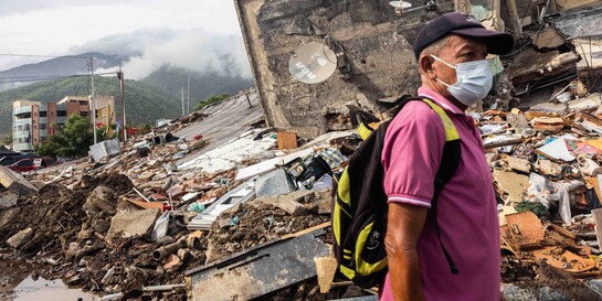 Ein Mann mit Maske läuft nach dem Erdbeben in Venezuela an Trümmern vorbei