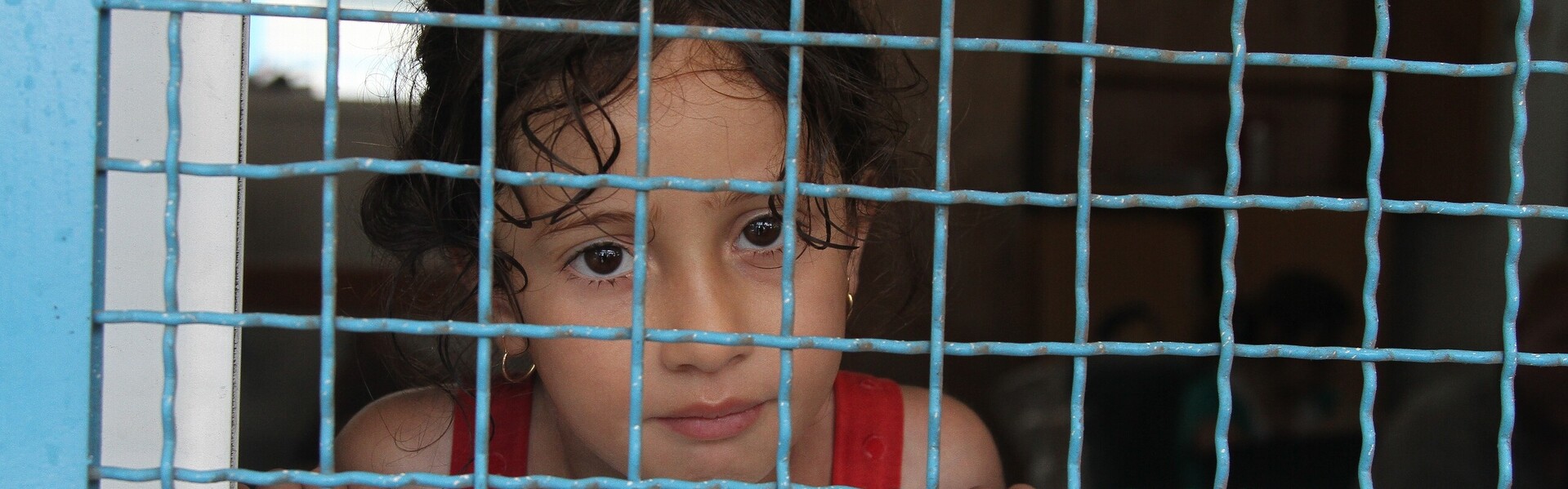 Ein Kind sitzt hinter Gittern im Gaza.