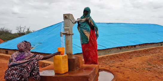 Frauen in Äthiopien füllen aus einem Brunnen Trinkwasser in gelbe Kanister ab