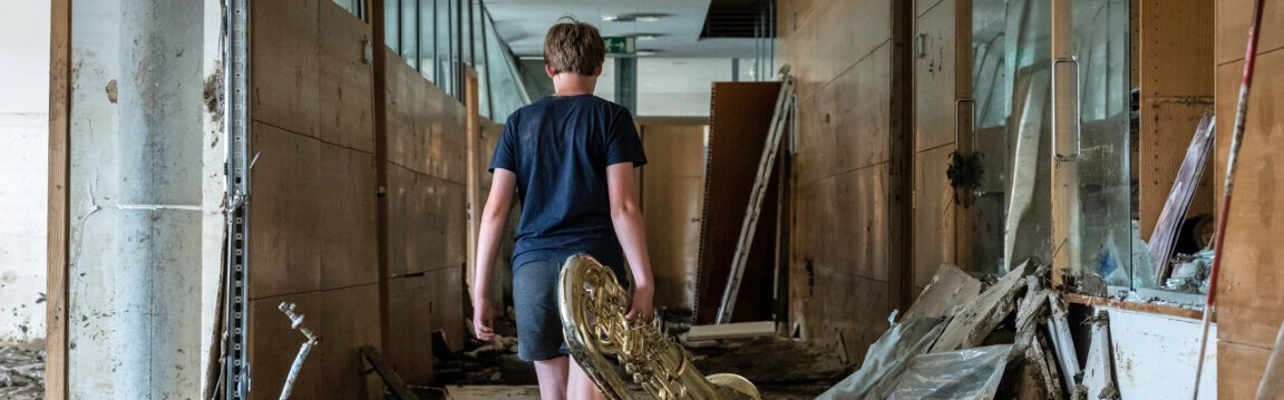 Eine Junge trägt seine Posaune durch das von den Fluten stark betroffene Peter-Joerres-Gymnasium in Ahrweiler