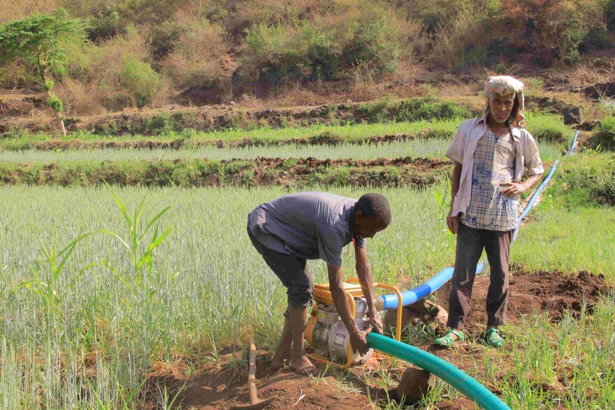 Zwei Männer bei der Arbeit neben einer Wasserpumpe auf einem Feld in Äthiopien