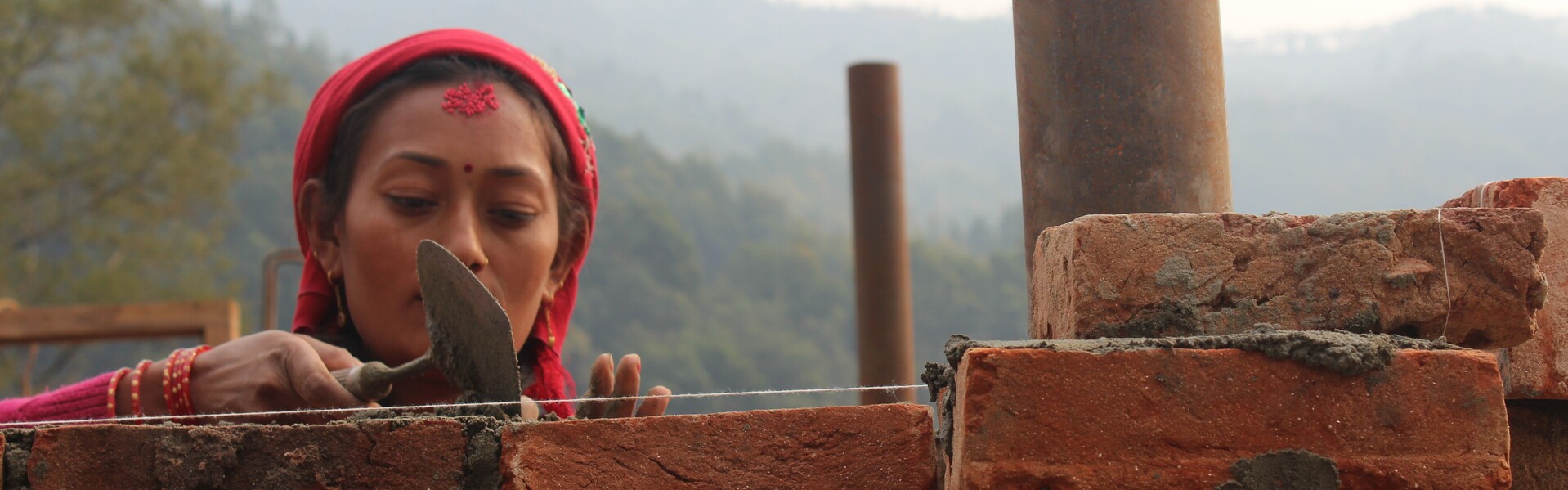 Die Maurerin Kopila baut die Mauer eines Hauses in Nepal wieder auf. 