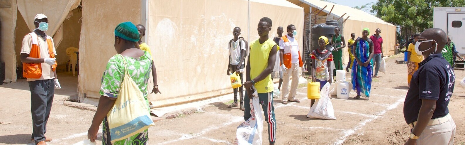 Menschen in Kenia warten auf vor einem Zelt der Hilfsorganisation World Vision auf ihre Lebensmittelrationen 