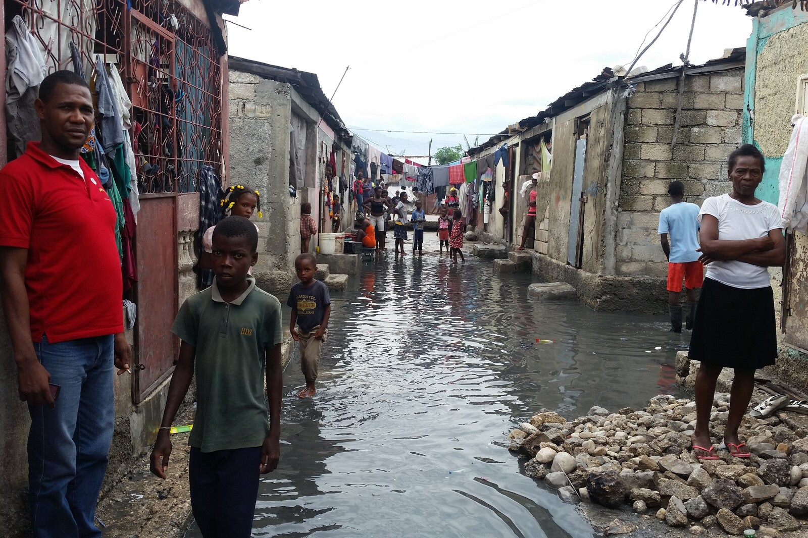 Menschen stehen vor ihren Wohnung in einer überfluteten Straße. Viele sind durch den Strum obdachlos geworden.