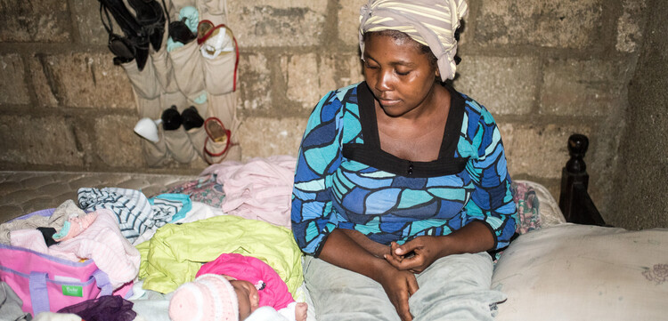Eine Frau sitzt mit ihrem Baby in einer Baracke in Haiti. Die Not der Menschen ist im ärmsten Land der westlichen Hemisphäre groß.