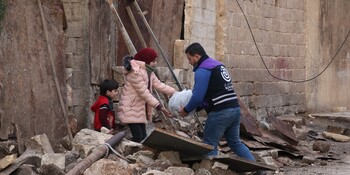 Ein Helfer überreicht Menschen in Syrien ein Paket