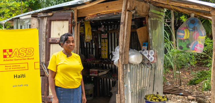 Eine Frau steht in Haiti vor einem Haus