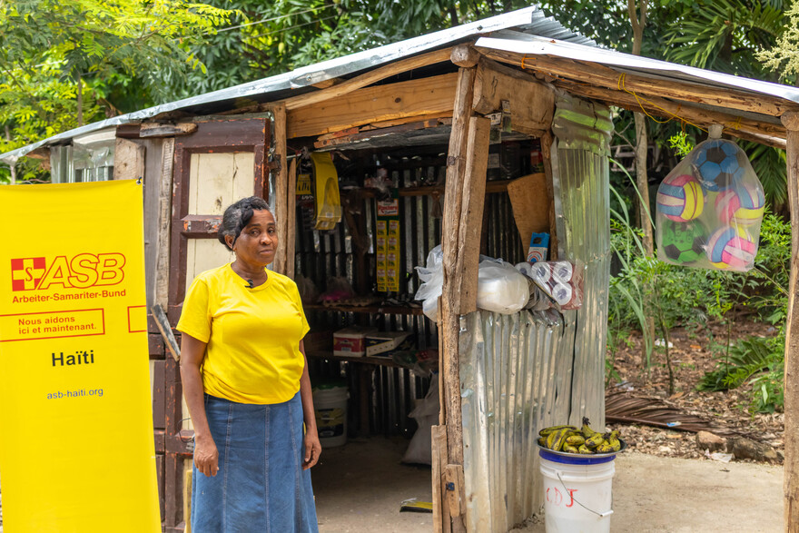 Eine Frau steht in Haiti vor einem Haus