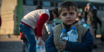 Ein Helfer verteilt Wasser an Menschen in Syrien