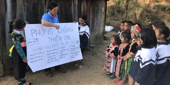 Ein Helfer von World Vision unterrichtet Kinder in einer vietnamesischen Schule richtiges Verhalten bei einer Naturkatastrophe