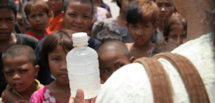 Zyklon in Birma: eine Malteser Mitarbeiterin erklärt die Anwendung des Wasseraufbereitungsmittels