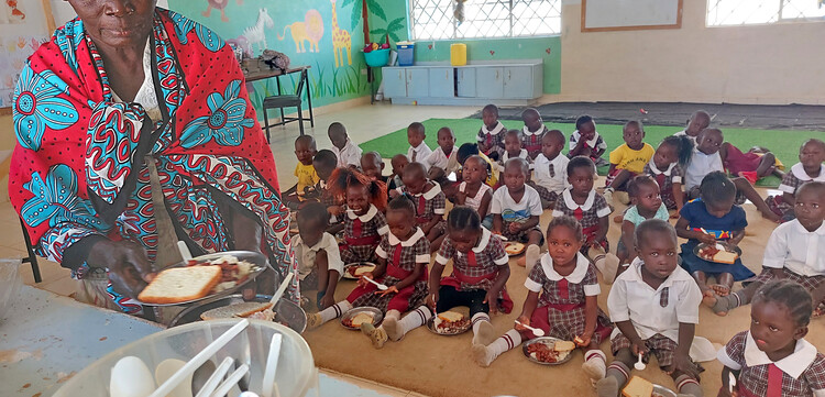 Eine Schulklasse sitzt zum Essen auf dem Boden