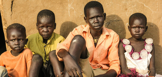 In Uganda sitzt eine Flüchtlingsfamilie. Sie sind Flüchtlinge aus Südsudan.