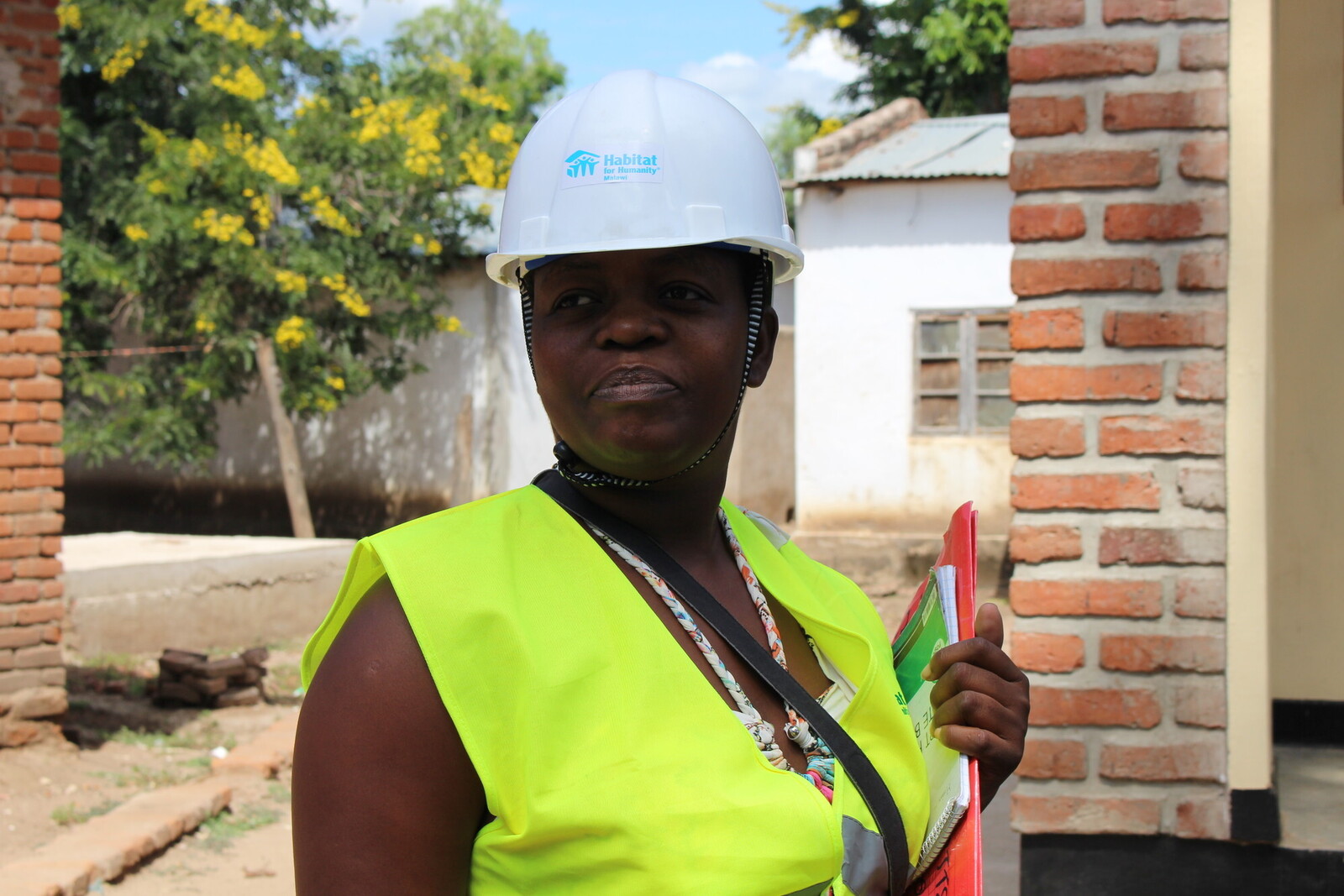 Eine Frau in Malawi mit gelber Warnweste und Schutzhelm