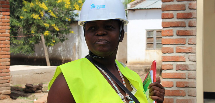 Eine Frau in Malawi mit gelber Warnweste und Schutzhelm Eine Frau in Malawi mit gelber Warnweste und Schutzhelm