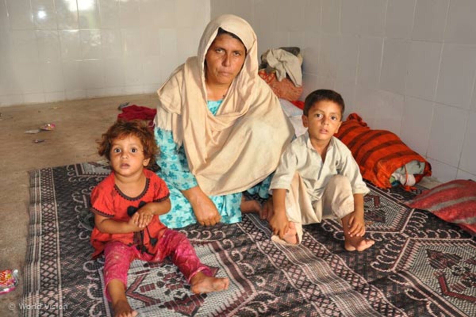 Flut Pakistan: Frau mit Kindern in Notunterkunft