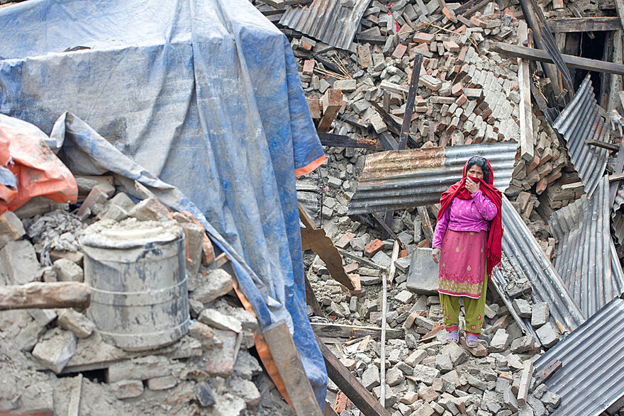 Eine Frau inmitten der Zerstörung, die ein Erdbeben 2015 in Nepal hinterließ.