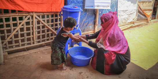 Corona-Prävention Bangladesch: Eine Helferin zeigt einem Jungen, wie richtiges Händewaschen geht